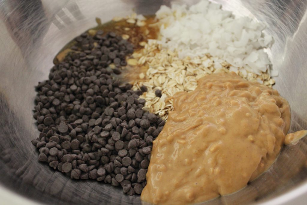 Mixing ingredients for no-bake peanut butter, chocolate, coconut, oatmeal balls.
