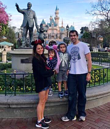 Family pose for picture in front of Sleeping Beauty Castle at Disney.